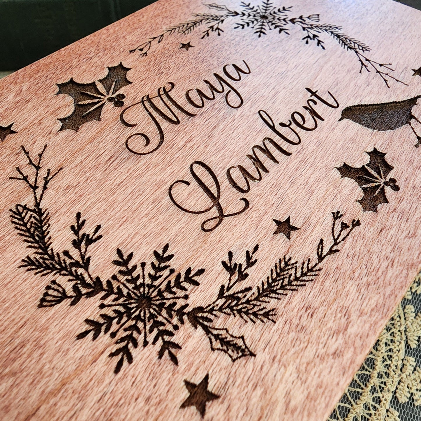 close up image of a Wooden Music Box custom made with a decorative Christmas Wreath theme engraving and your name choice centered. Choose color, song, add personalized message to create a one-of-a-kind keepsake