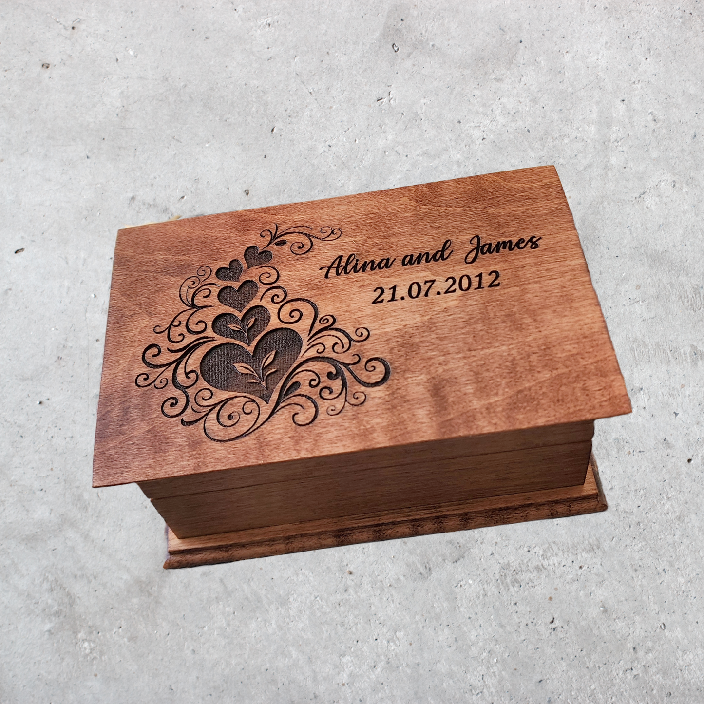 Heart jewelry box with engraved heart design and your names and date on a concrete surface
