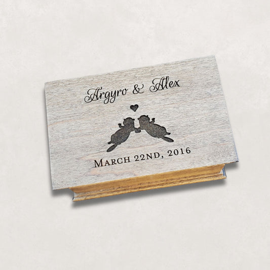 Wooden music box with your names, 2 otters silhouette holding hands with a heart above them and a date underneath engraved on the top, choose from 9 colors, add your song and personalized engraving