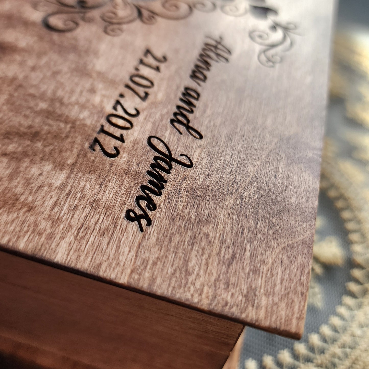 Wooden jewelry box with engraved text names and date personalized 'Alina and James 21.07.2012' on a decorative background