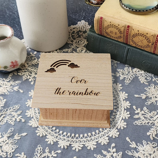 Small handcrafted wooden music box engraved with a rainbow and the words “Over the Rainbow"