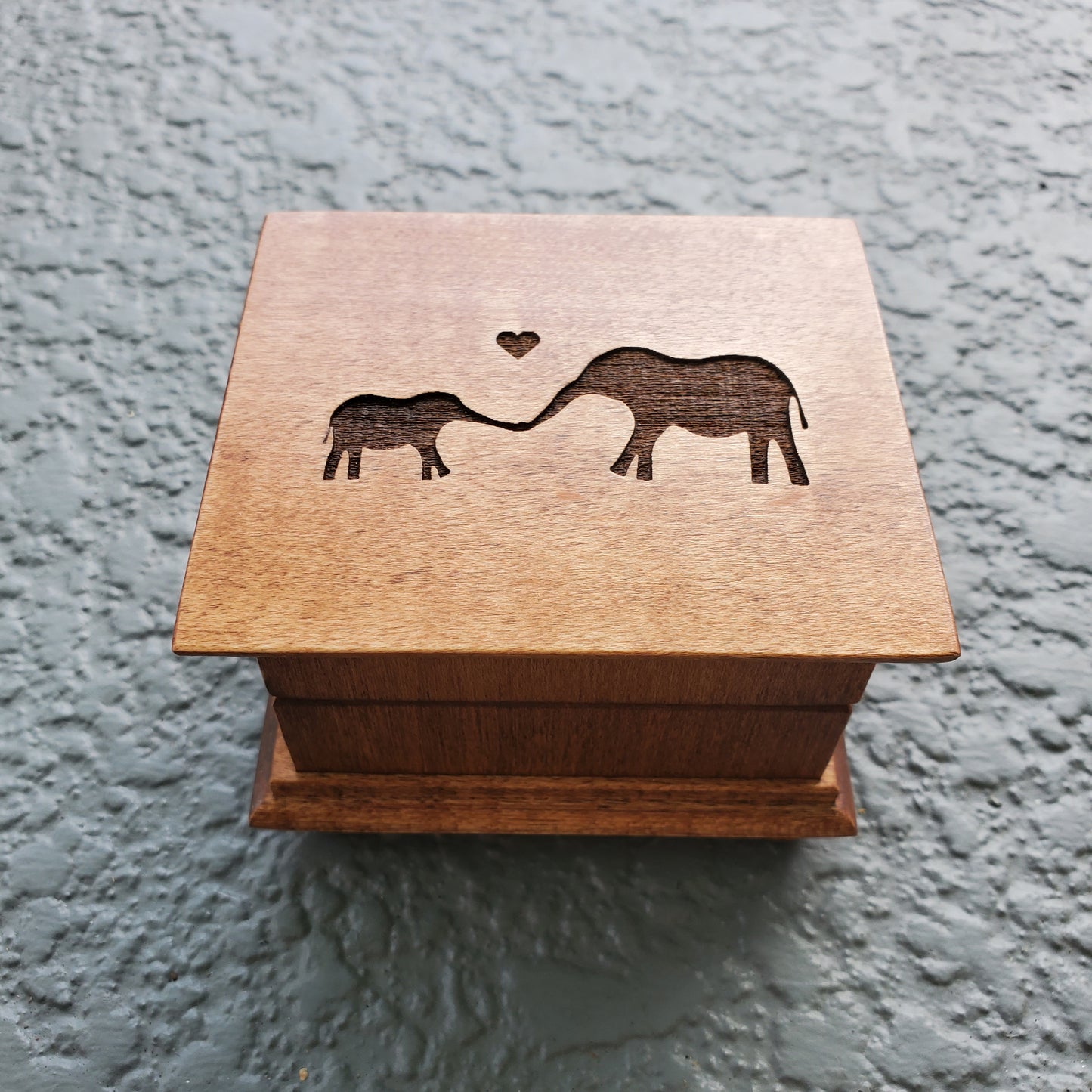 wooden music box in chestnut, it has a baby and momma elephant engraved on top, choose song, color, add a personalized message to the bottom side of box