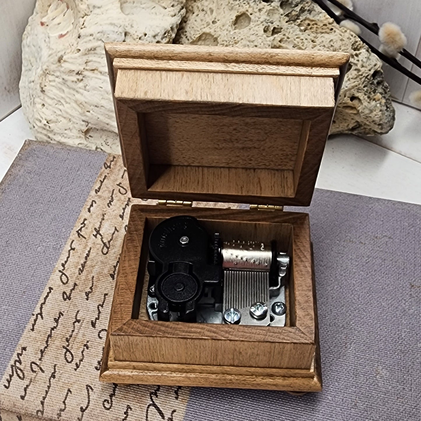 music box with an open lid, showing the wind up music box movement, choice of song, choice of color