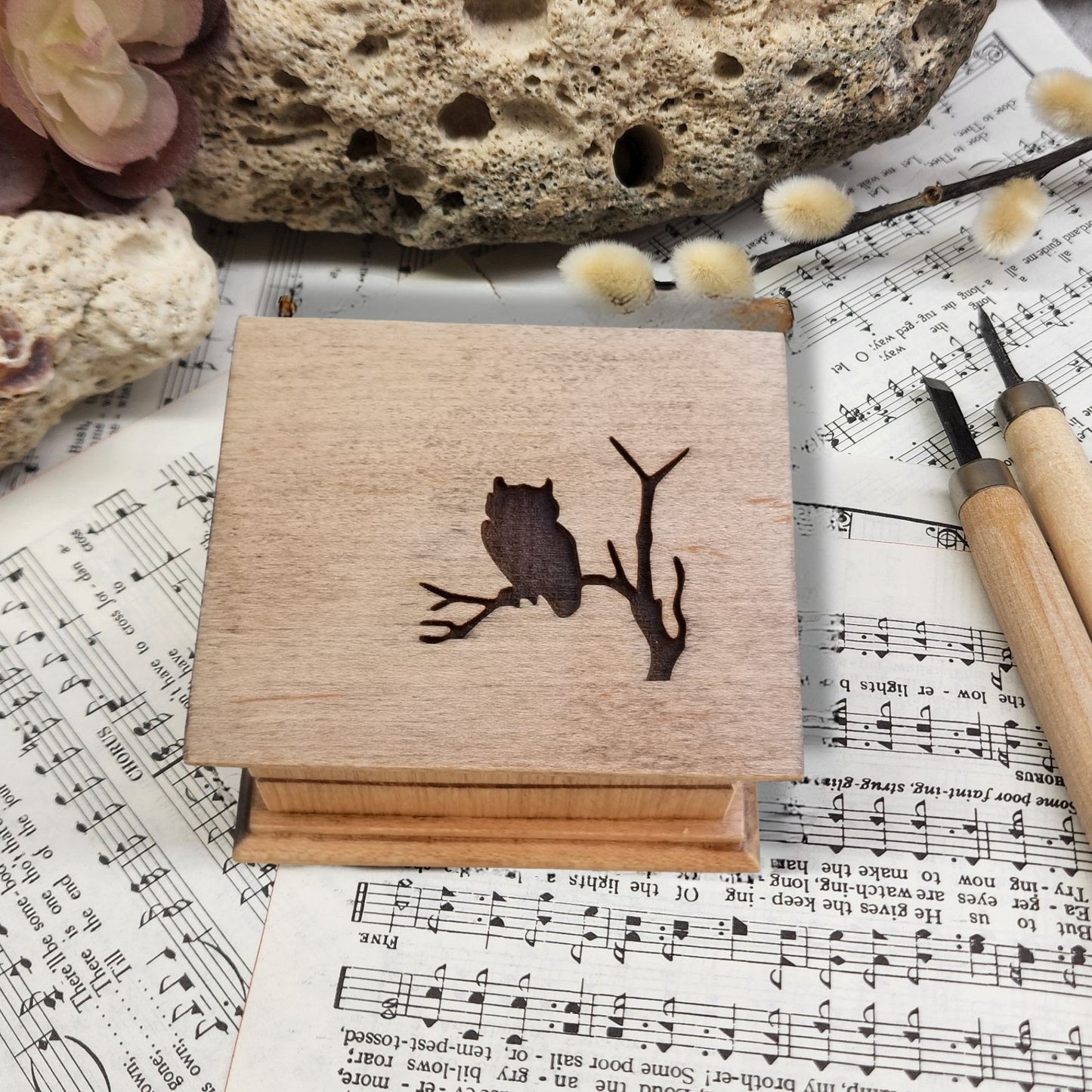 Wooden box with owl design on sheet music and rocks