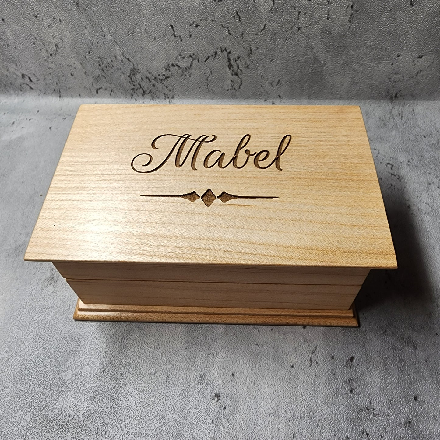 wooden jewelry box with a name engraved on it with a beautiful script font, and a decorative underline. it plays your song in music box sound when you open it, and you can choose the color and add a personalized message to the bottom side of box