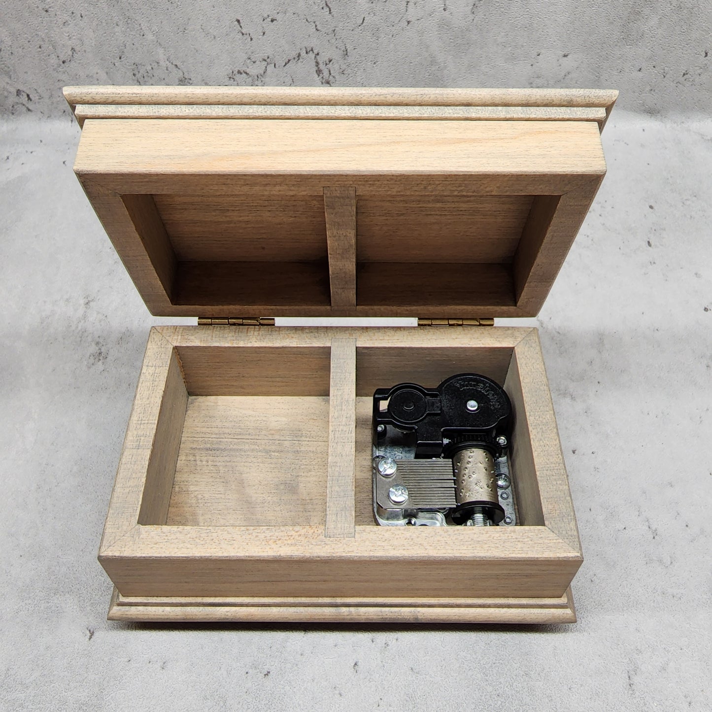 wooden jewelry box with an open lid showing a divider in the middle with the wind up music box movement on the right side and an additional compartment for some jewelry on the left. Choose from 80 different colors, customizable engraving options and a personalized message to the back side of the box to create a one-of-a-kind gift for your anniversary.