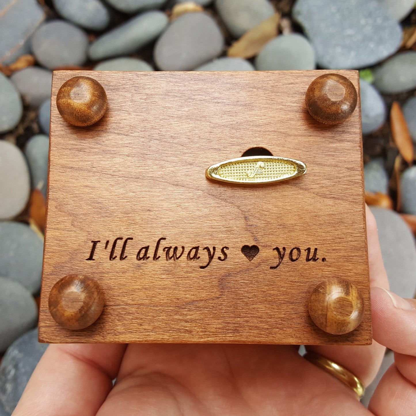 music box with personalized engraving on the bottom side of the box showing wind up key and the feet of the music box