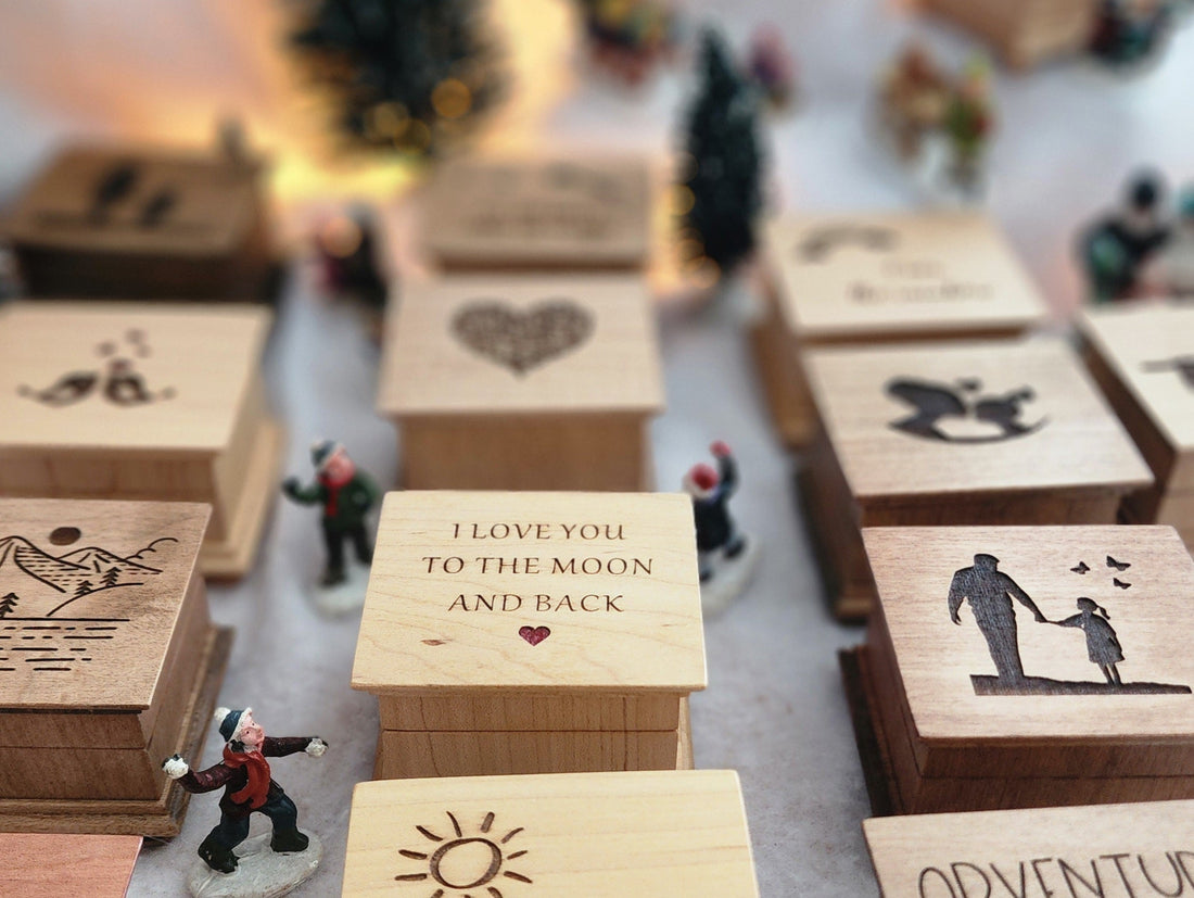 Cozy Christmas display of handcrafted wooden music boxes surrounded by miniature trees and holiday lights, personalized designs by SimplyCoolGifts.