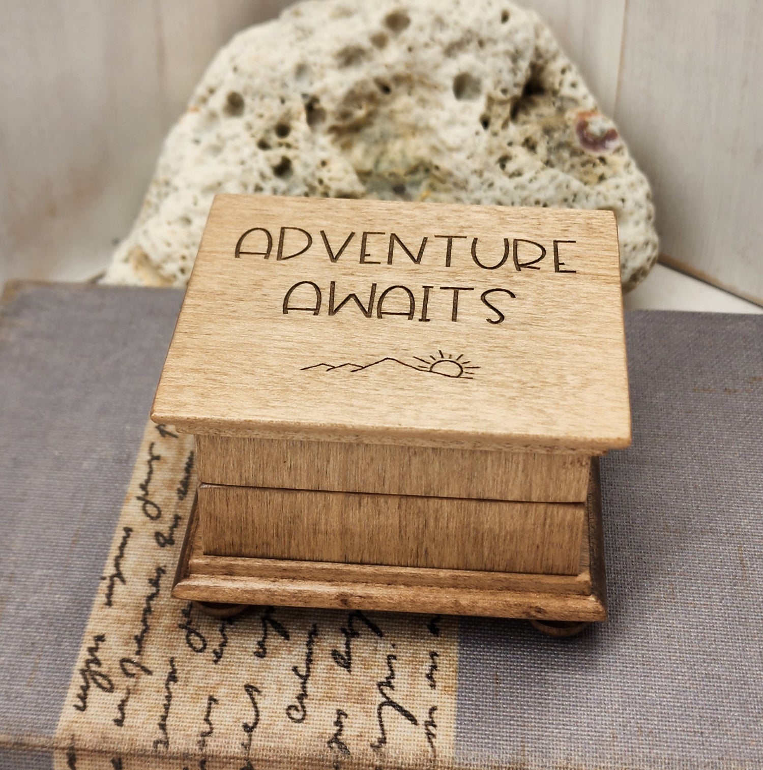 Adventure Awaits Music Box engraved with a minimalistic design of mountains and the sun