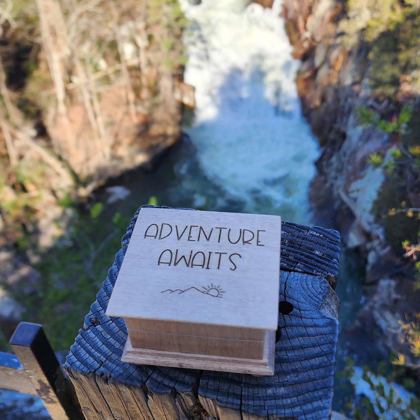 Music Box with 'Adventure Awaits' on a wooden ledge with a scenic background