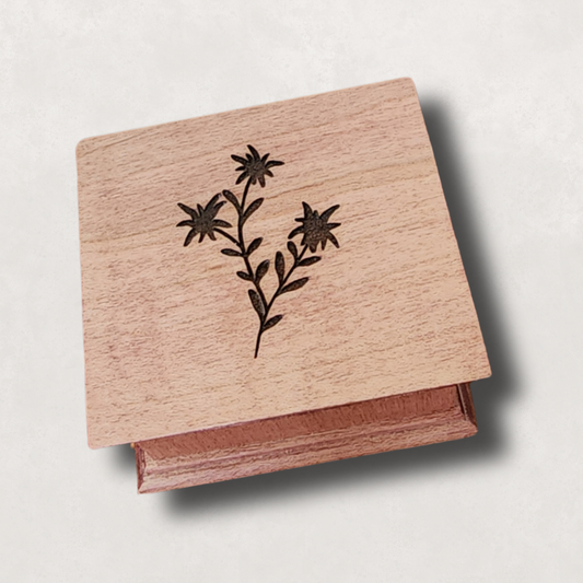 Wooden music box with edelweiss flower design on a light gray background