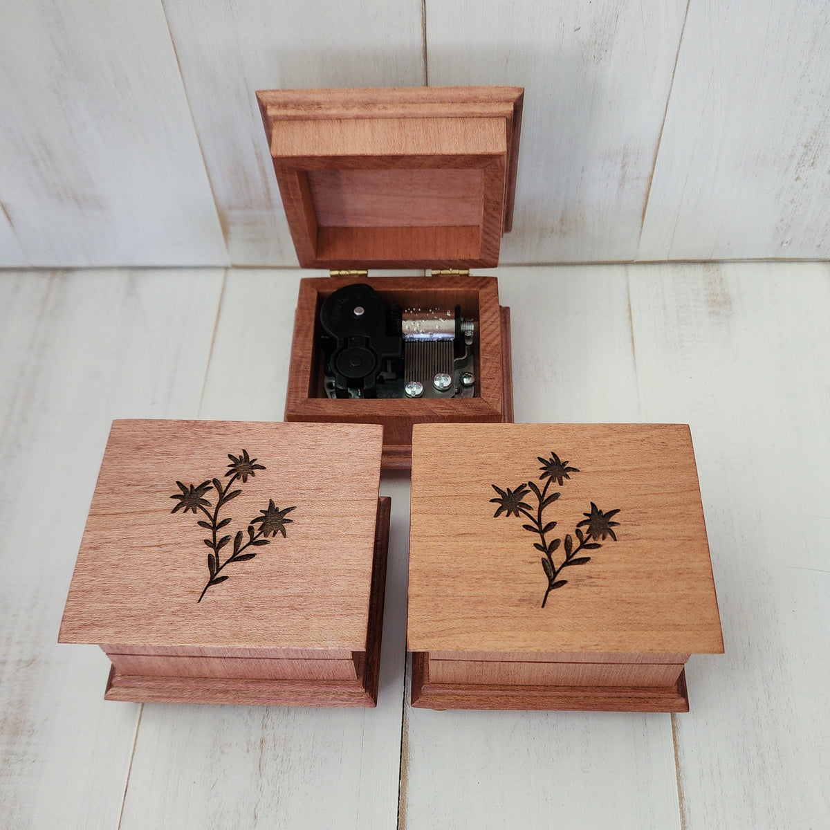 wooden music boxes 3 pieces on a white washed wooden surface. 1 o the 3 is opened showing the 18 note music box mechanism