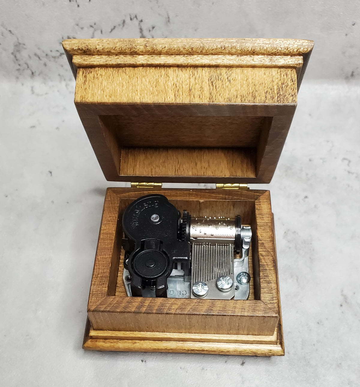 Small wooden music box showing a walnut music box with open lid with the 18 note wind up music box movement inside, you can choose from 70 songs, 16 colors 