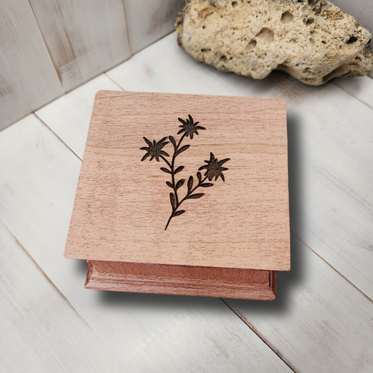 Wooden music box with edelweiss floral design on a light wooden surface