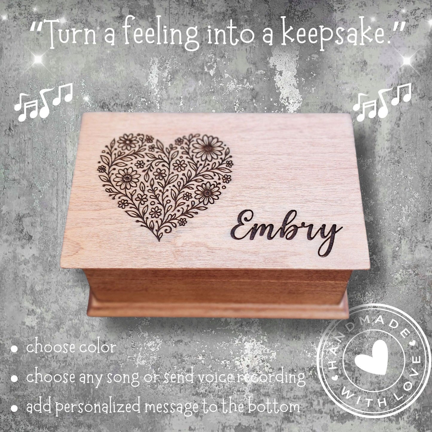 Wooden box with floral heart design and engraved name on a textured gray background.