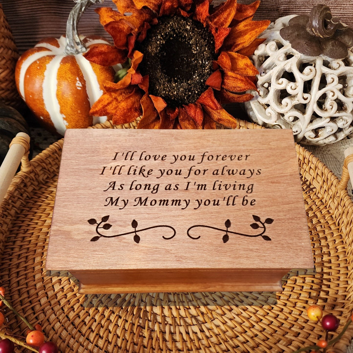 Handmade wooden music box engraved with the quote “I’ll love you forever, I’ll like you for always, as long as I’m living, my mommy you’ll be,” displayed on smooth river stones — sentimental personalized jewelry box for mom.