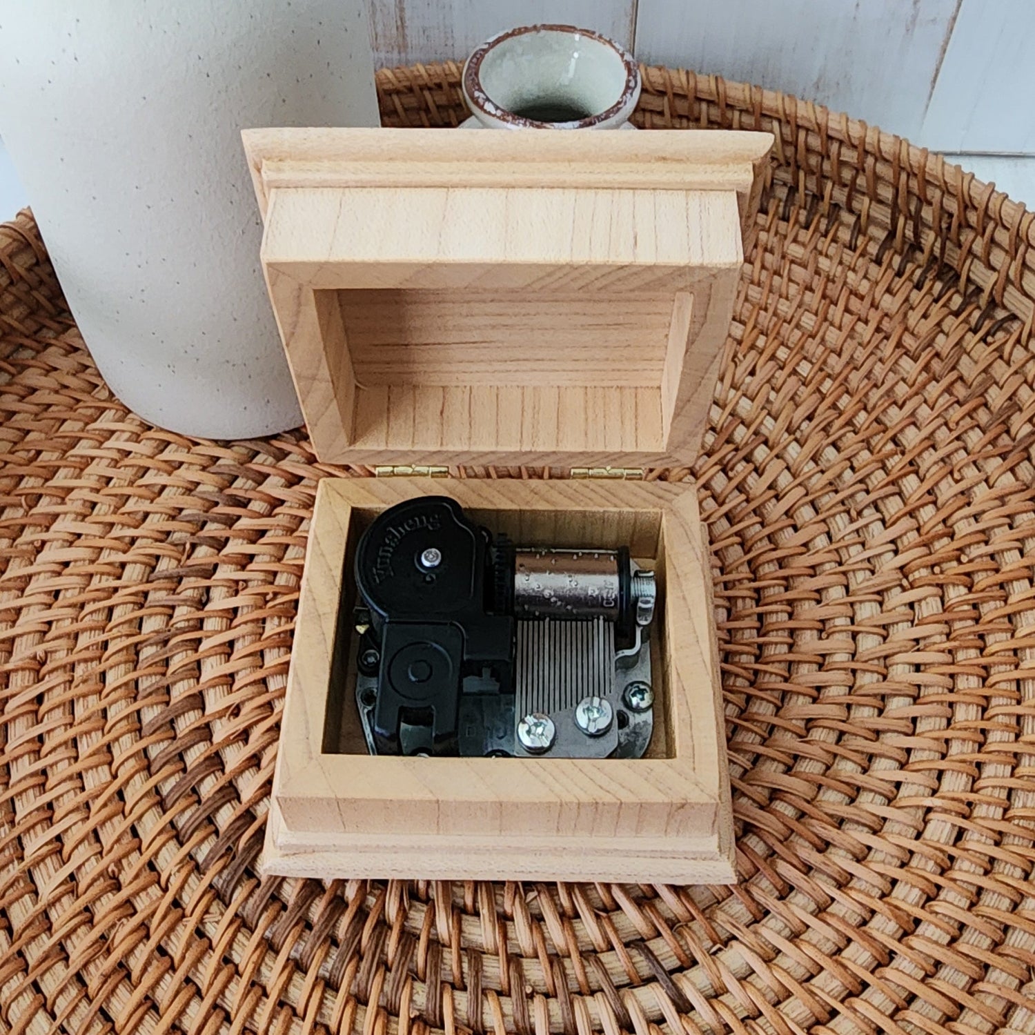 Wooden music box with open lid on a woven surface