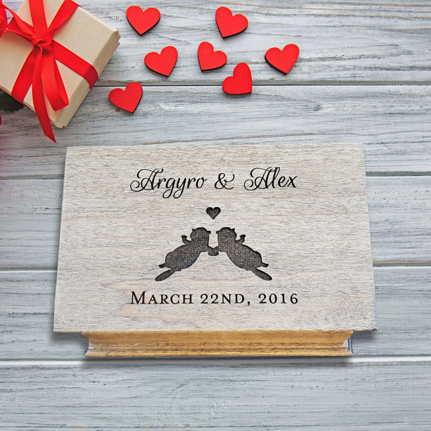 Wooden music box with your names, 2 otters silhouette holding hands with a heart above them and a date underneath engraved on the top, choose from 9 colors, add your song and personalized engraving