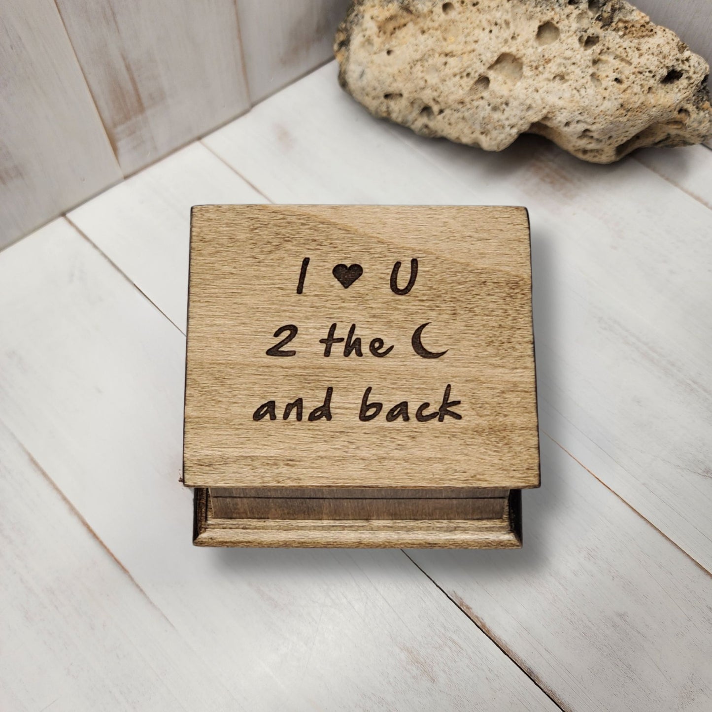 Wooden box with 'I ❤️ U 2 the moon and back' engraving on a light wooden surface. choose from 16 colors and 80 songs the create your personalized music box