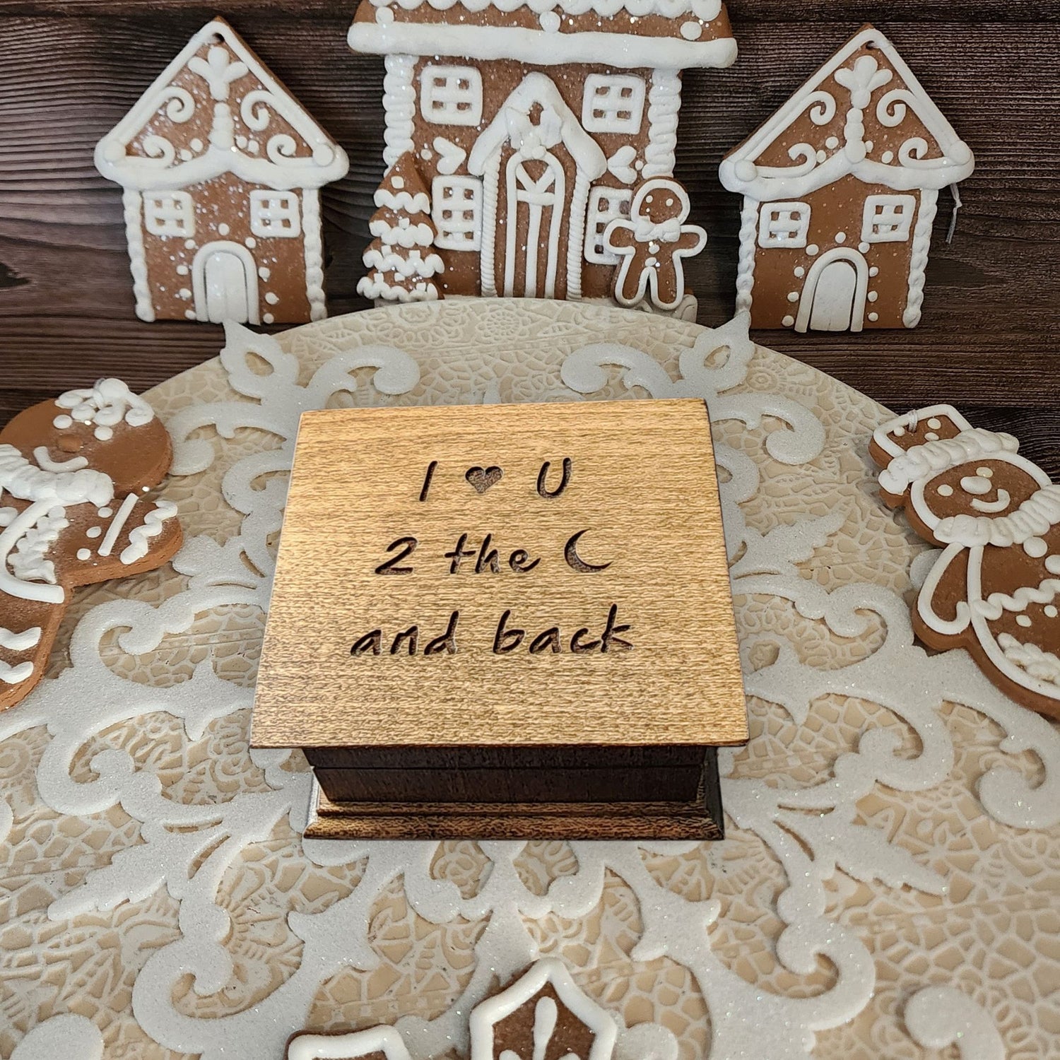 Wooden music box with 'I ❤️ U 2 the moon and back' engraving surrounded by gingerbread houses on a decorative Christmas theme setting