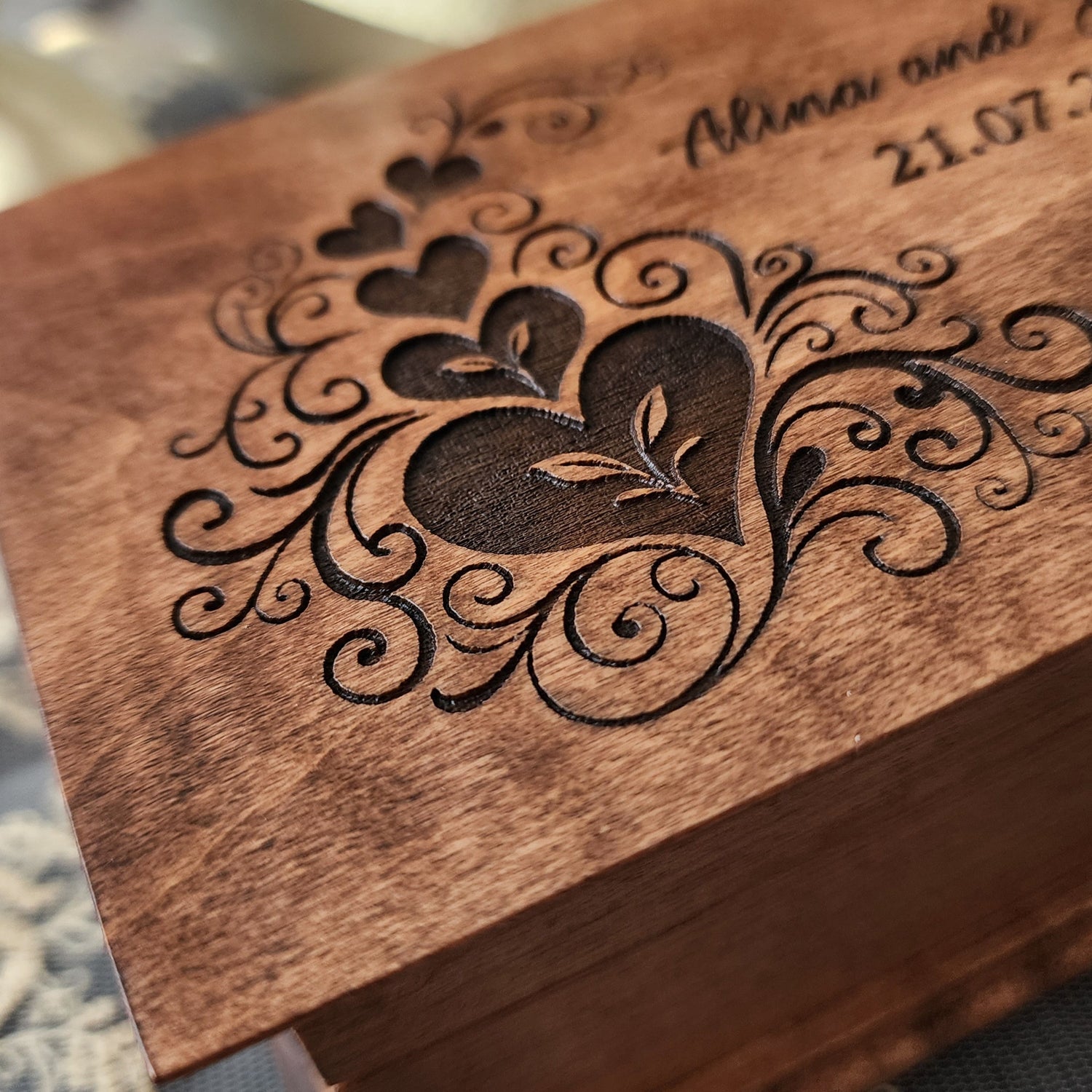 Wooden box with intricate laser cut design on a textured fabric background