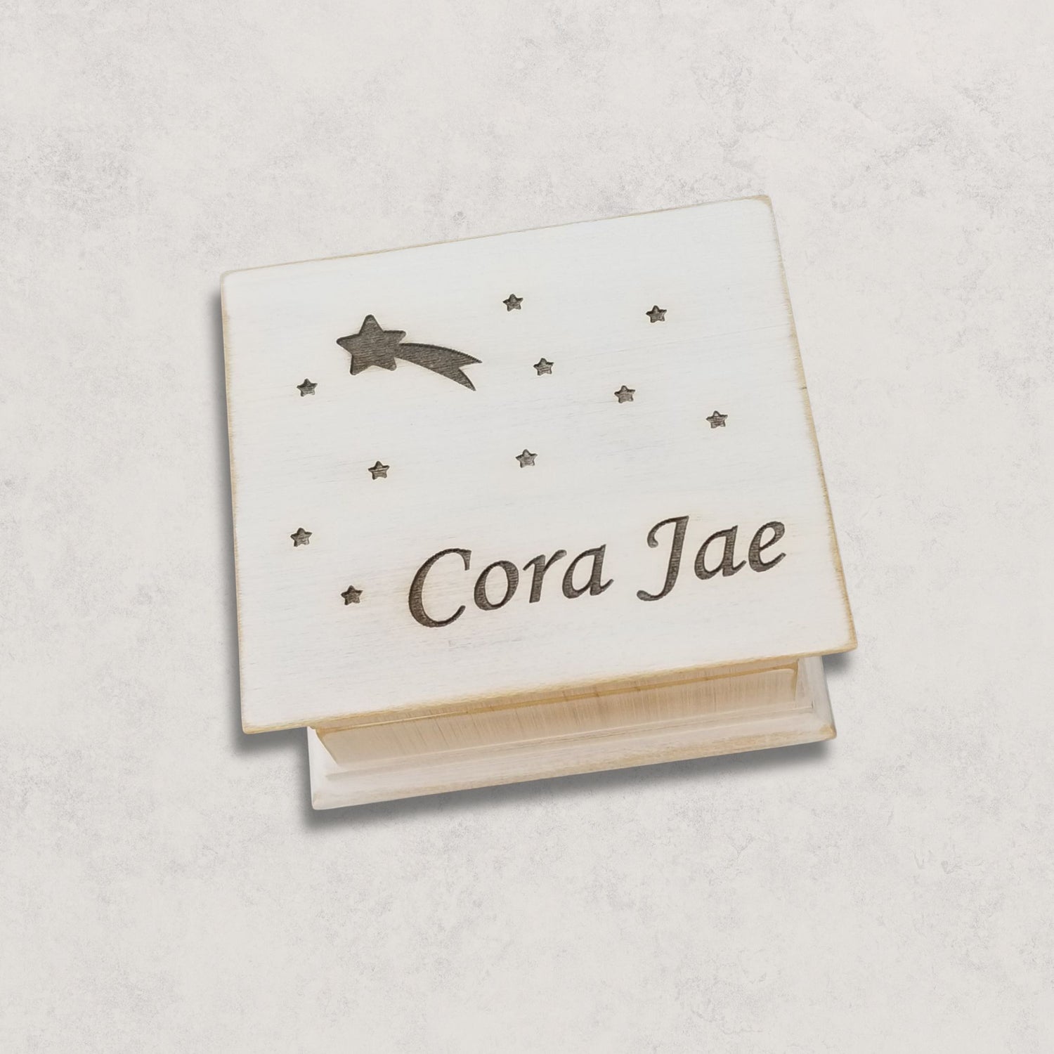 Wooden music box engraved with 'Cora Jae' , shooting star and star engraved on a light gray background