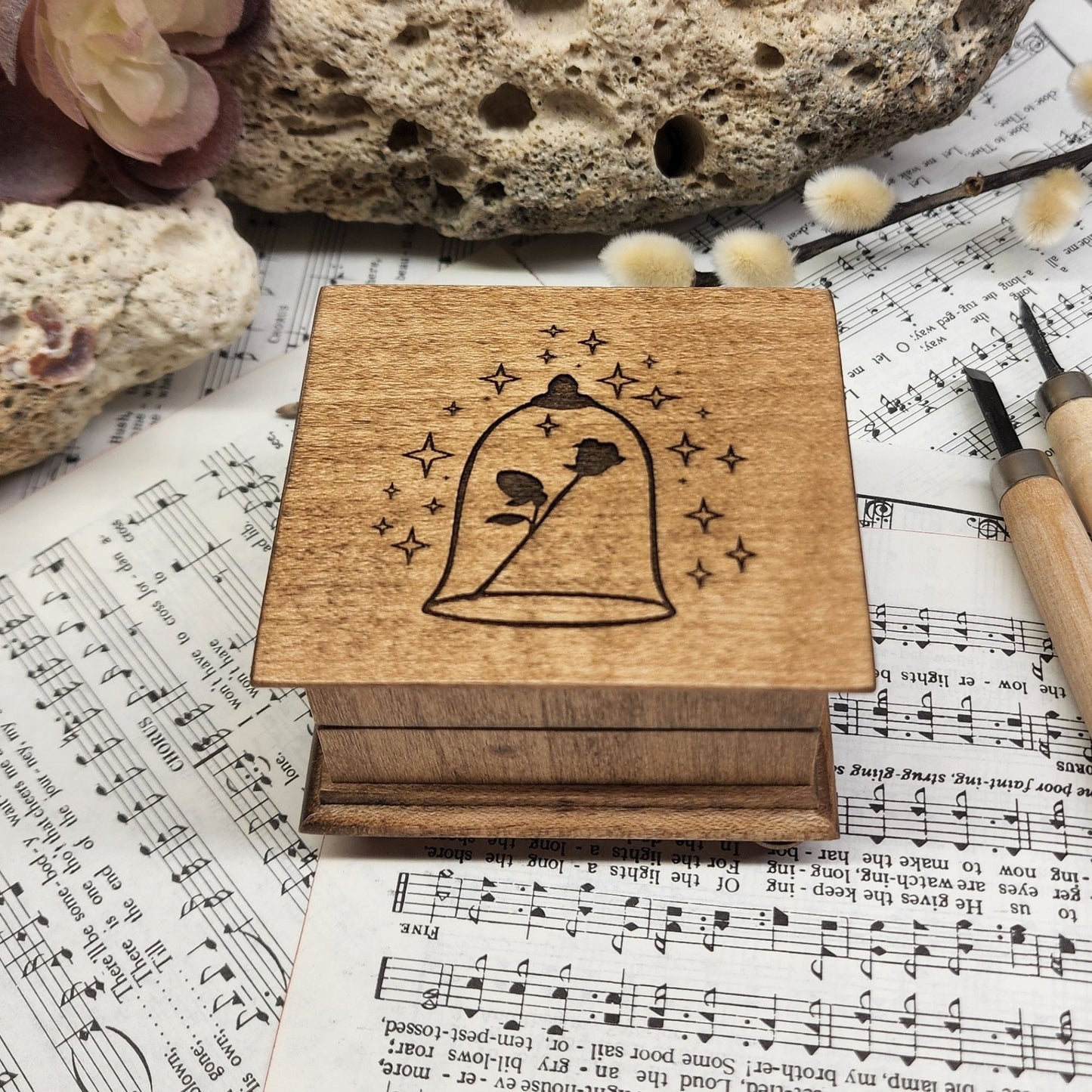 Small handcrafted wooden wind-up music box with engraved lid with rose under glass dome with stars surrounding it. 