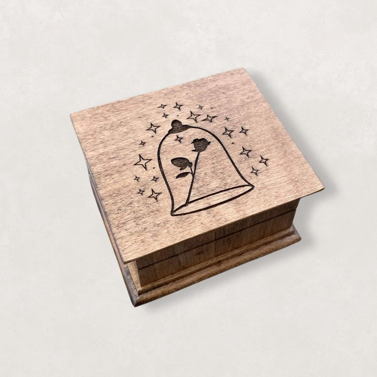 Small handcrafted wooden wind-up music box with engraved lid with rose under glass dome with stars surrounding it. 