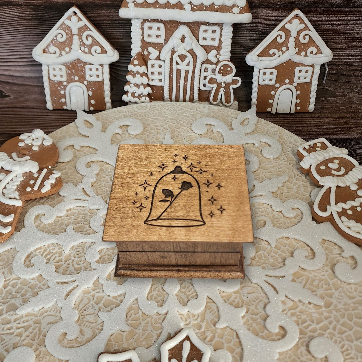 Small handcrafted wooden wind-up music box with engraved lid with rose under glass dome with stars surrounding it. 