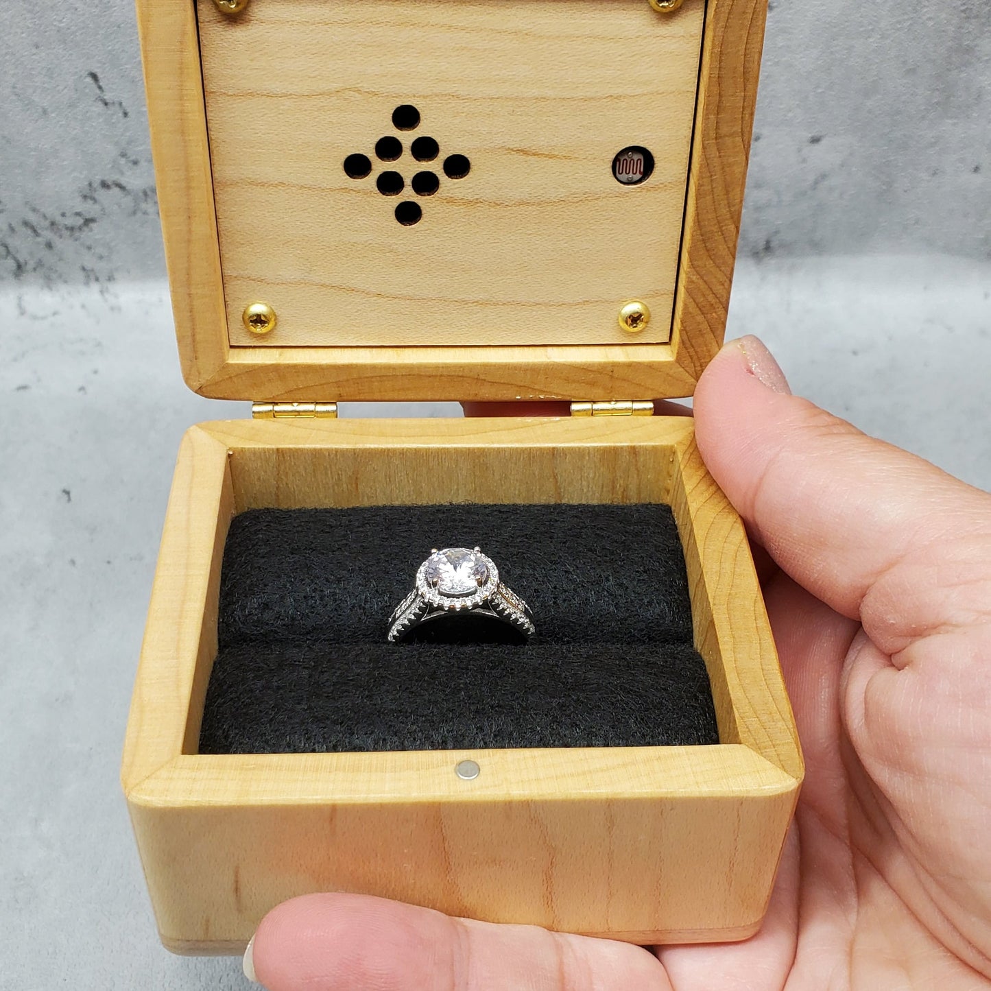 Wooden ring box with a ring inside, held by a hand