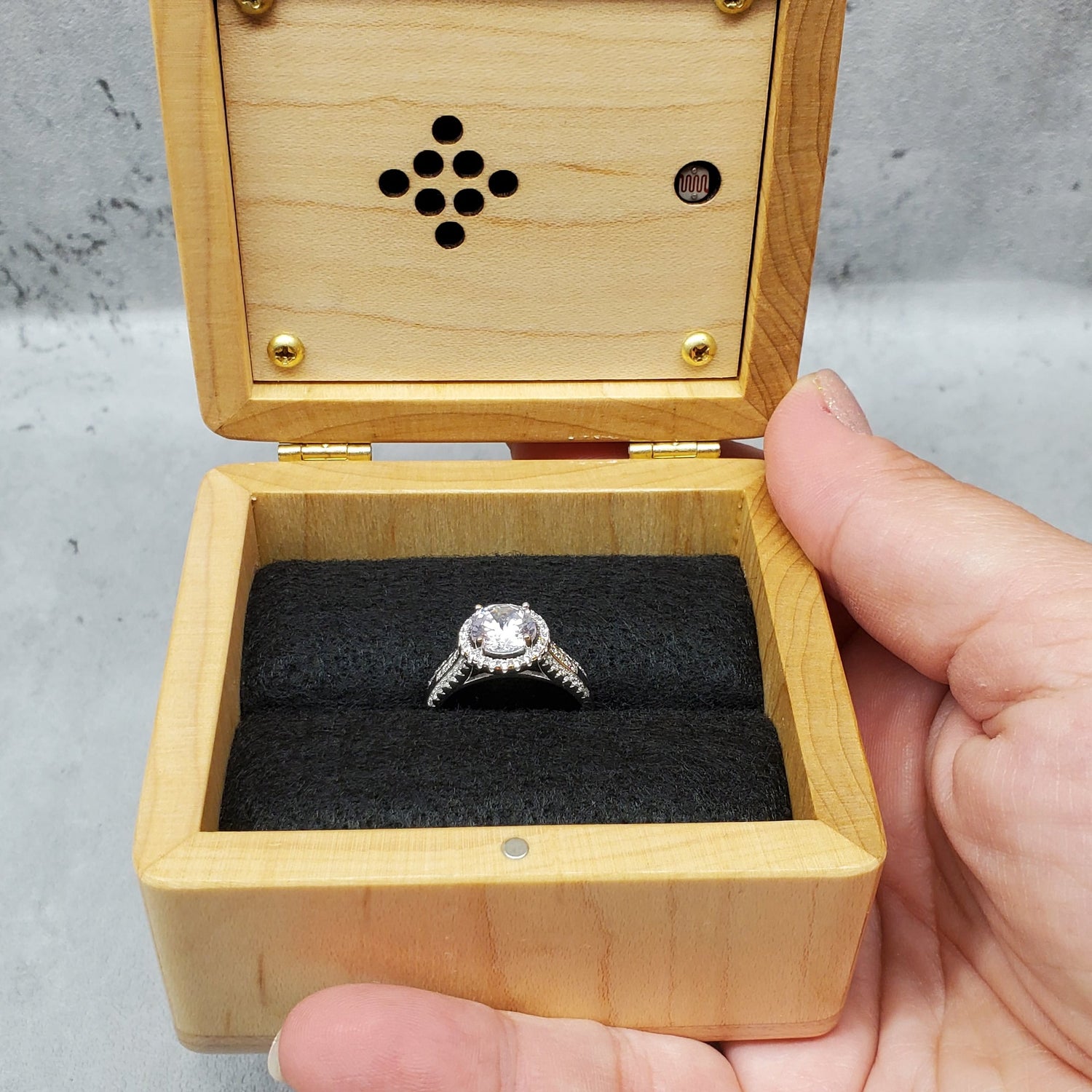Wooden ring box with a ring inside, held by a hand