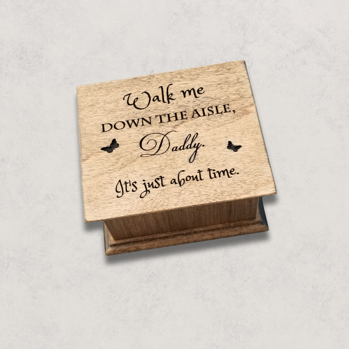 Wooden box with engraved message on a light gray background
