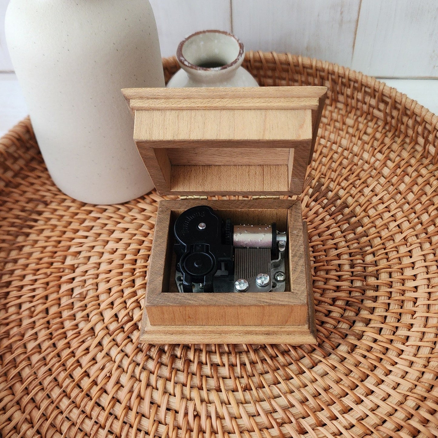 Wooden music box with classic wind up mechanical components on a woven surface