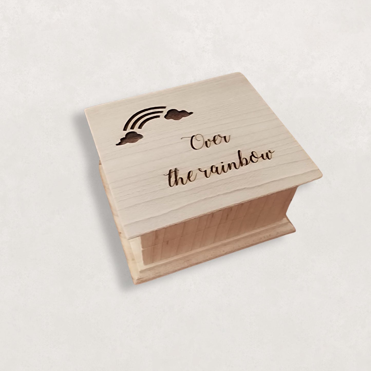 Wooden music box with engraved text 'Over the rainbow' on a light background
