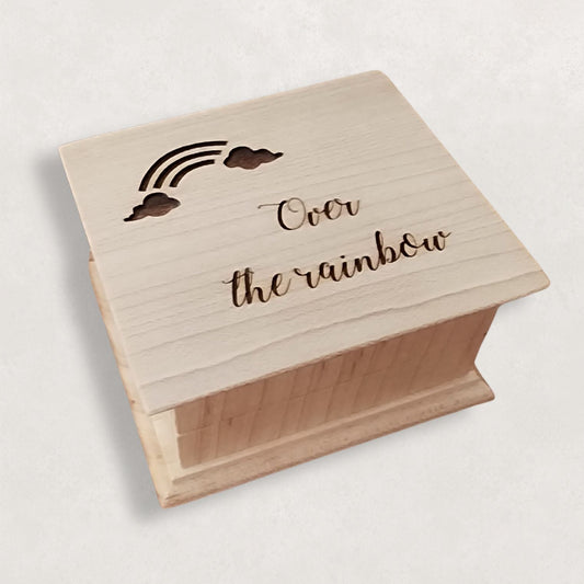 Wooden music box with engraved text 'Over the rainbow' on a light background