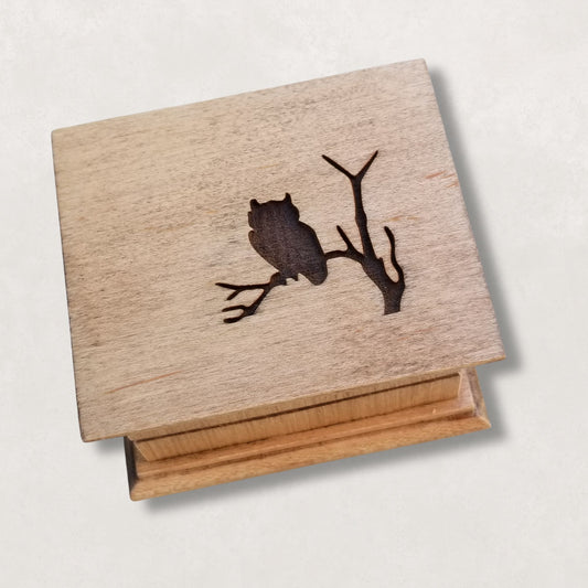 Wooden music box with an owl design on a light gray background