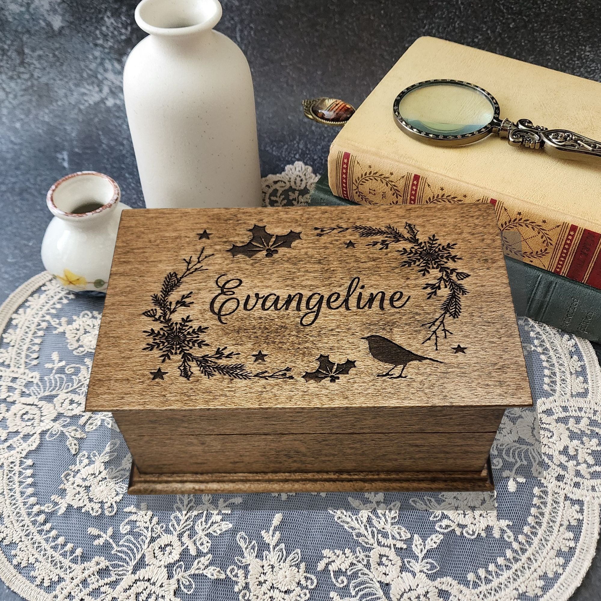 Christmas theme wreath with stars, a cardinal, and holly with a name centered in cursive font engraved on the top of a dark walnut music box with jewelry compartment, add any song or voice recording