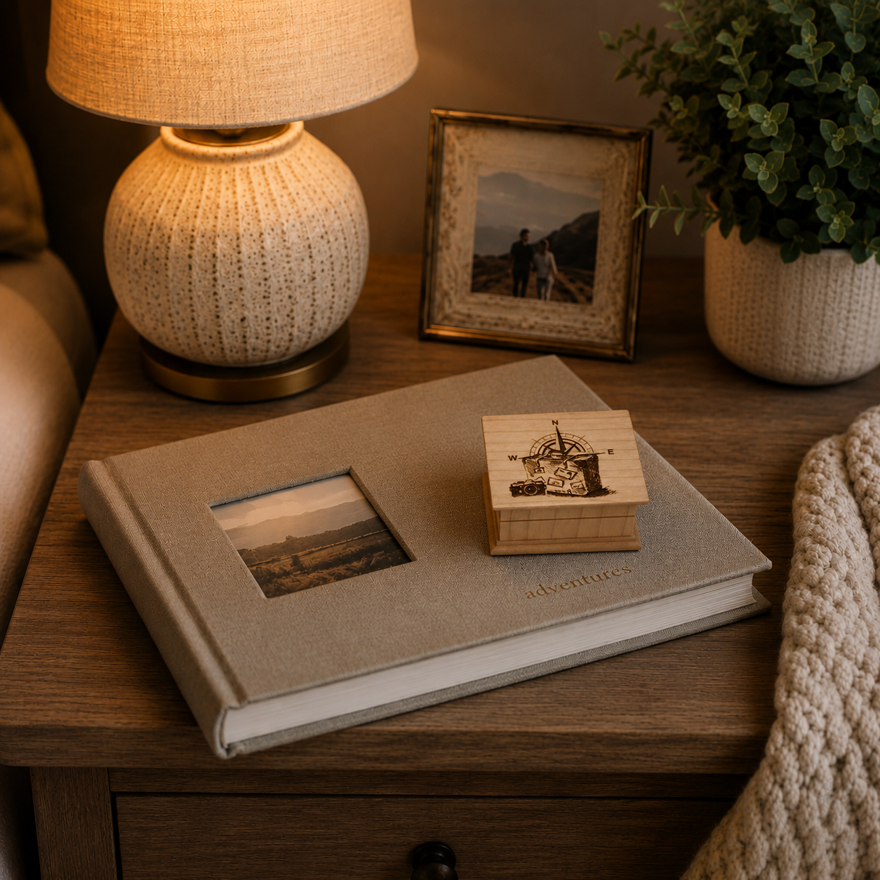 Decorative bedside table with a lamp, photo album, wooden music box, and framed picture.