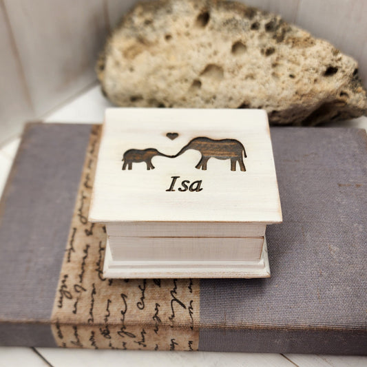 wooden music box with vintage white paint, it has a name and a baby and momma elephant engraved on top, choose song, color, add a personalized message to the bottom side of box