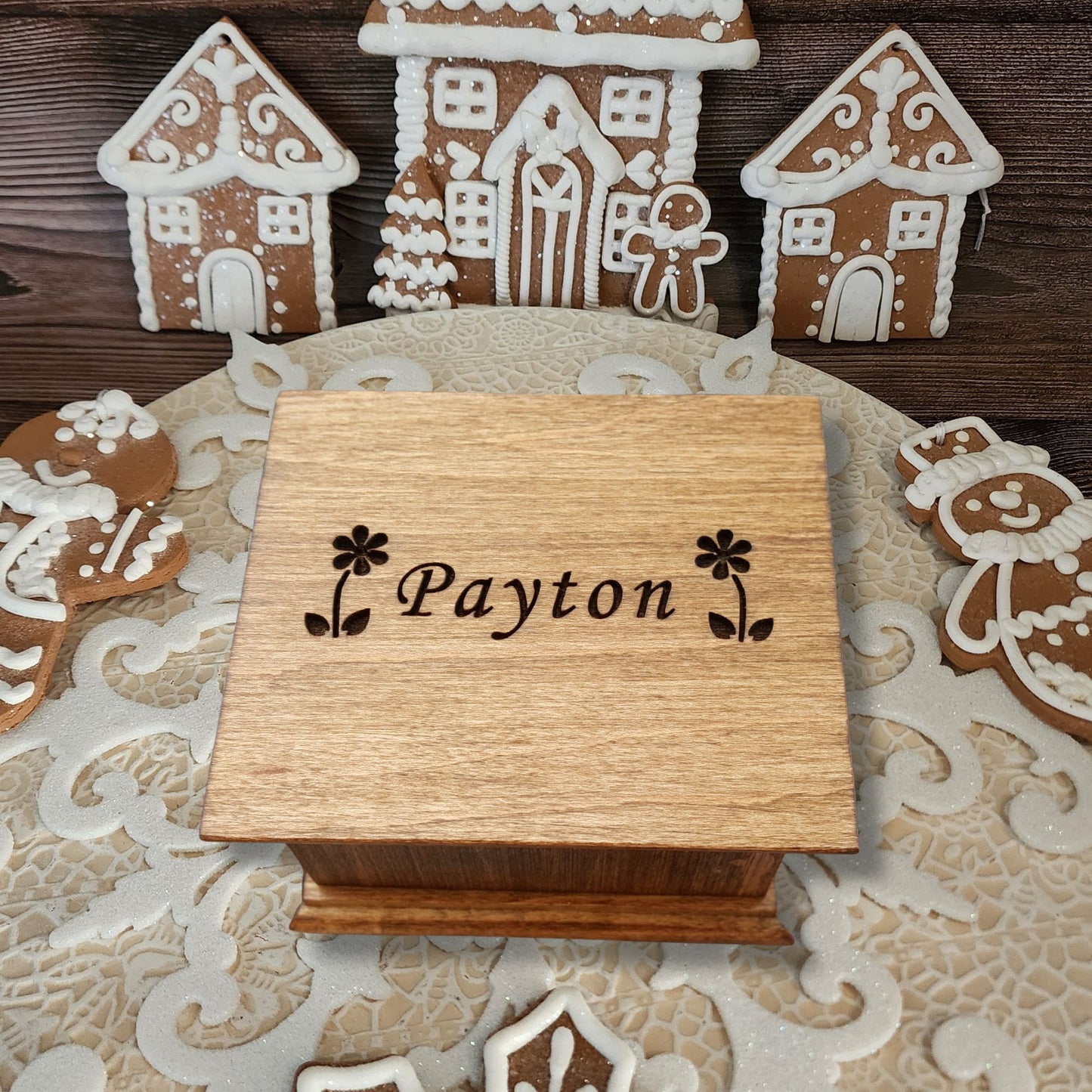 Wooden wind up style music box with 'Payton' engraving on a decorative surface with gingerbread houses.