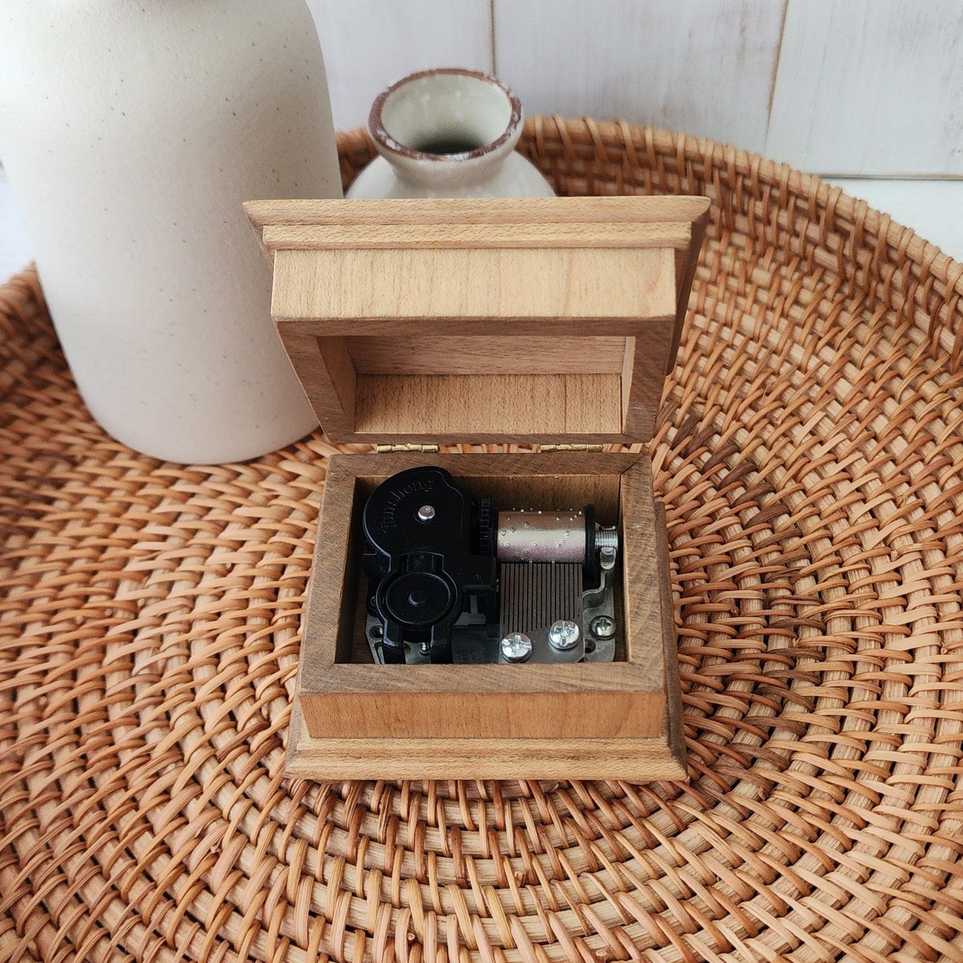 Wooden music box with mechanical components on a woven surface