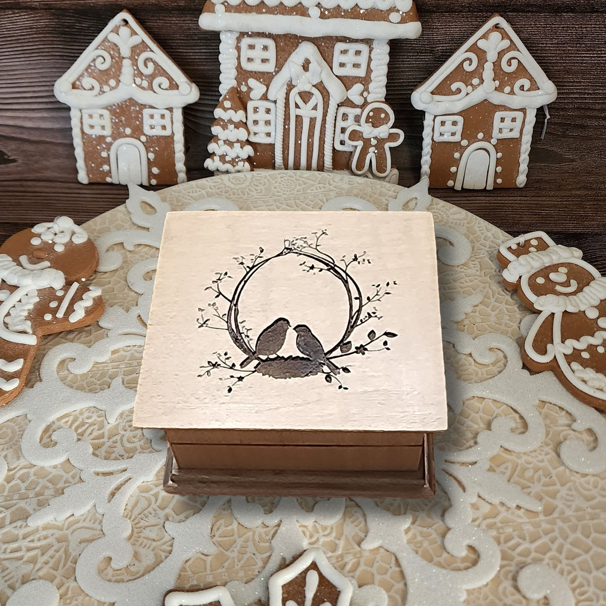 Wooden box with bird design on a decorative tablecloth with gingerbread houses.
