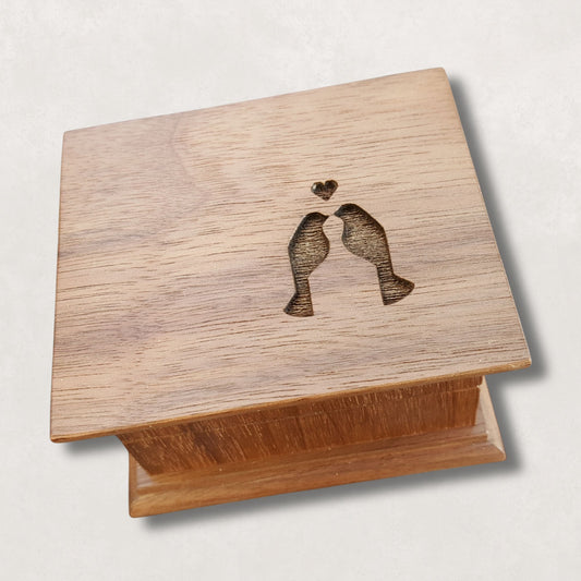 Wooden music box with engraved design of two love birds and a heart on a light background
