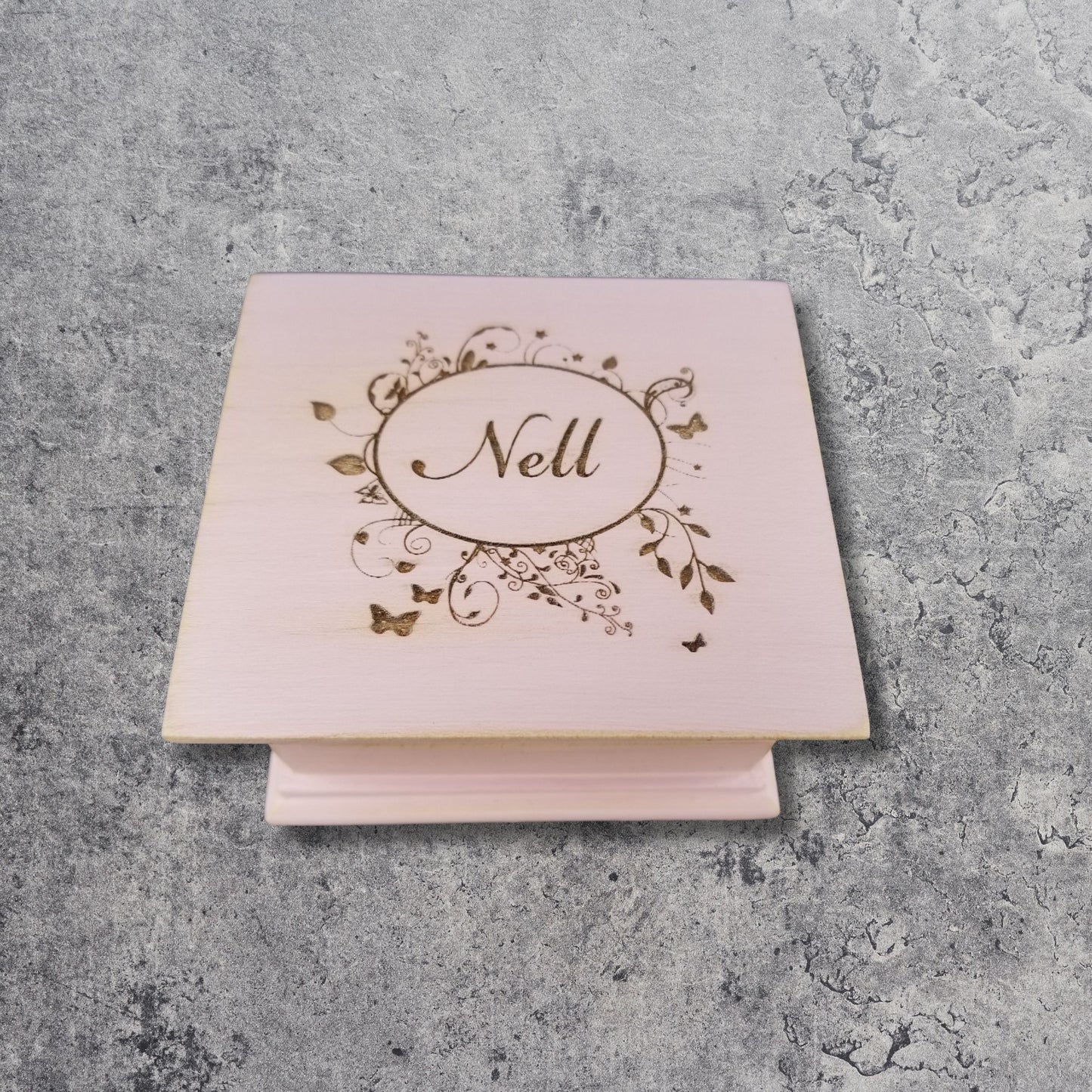 wooden music box in vintage pink color engraved with a floral oval frame and the name Nell 