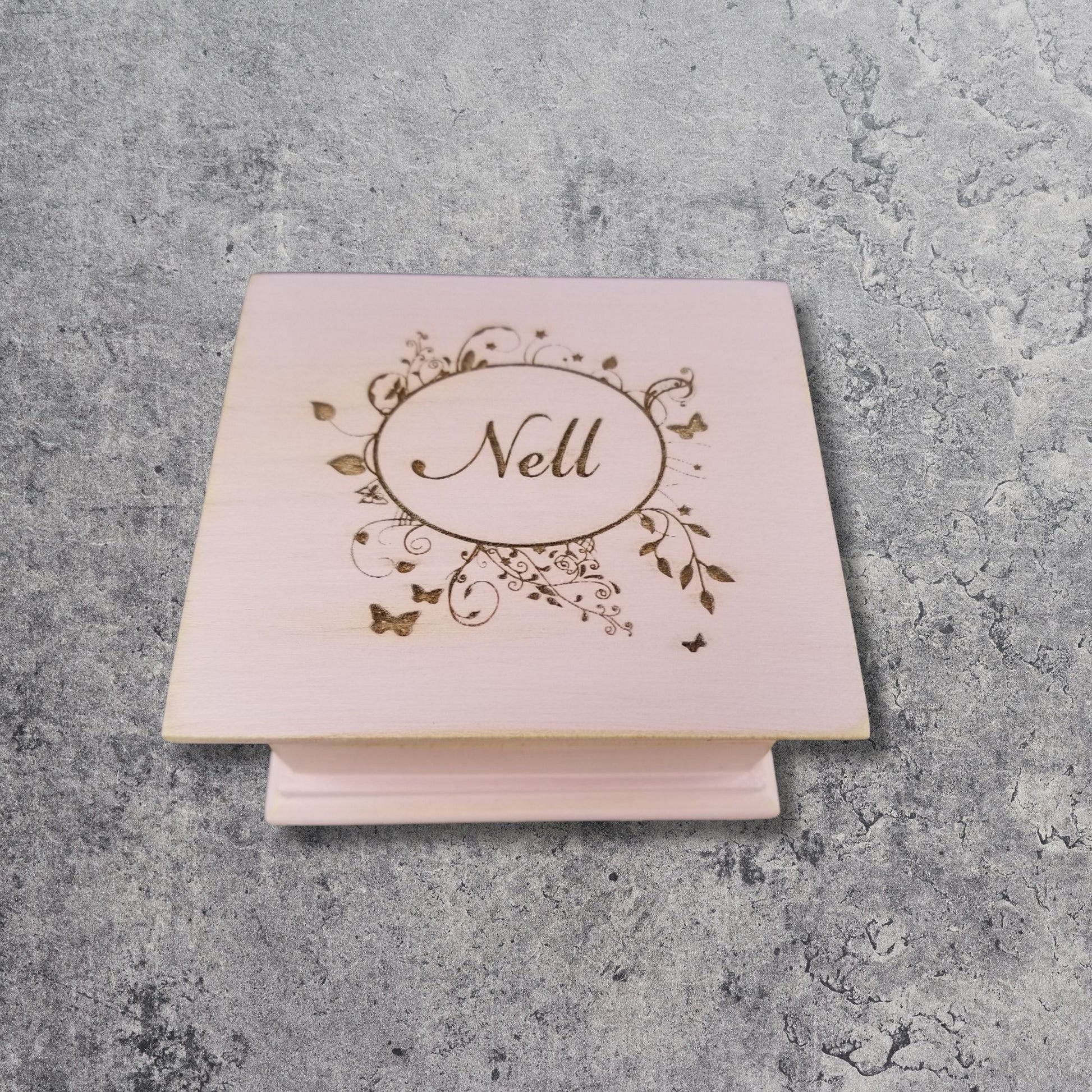 wooden music box in vintage pink color engraved with a floral oval frame and the name Nell 