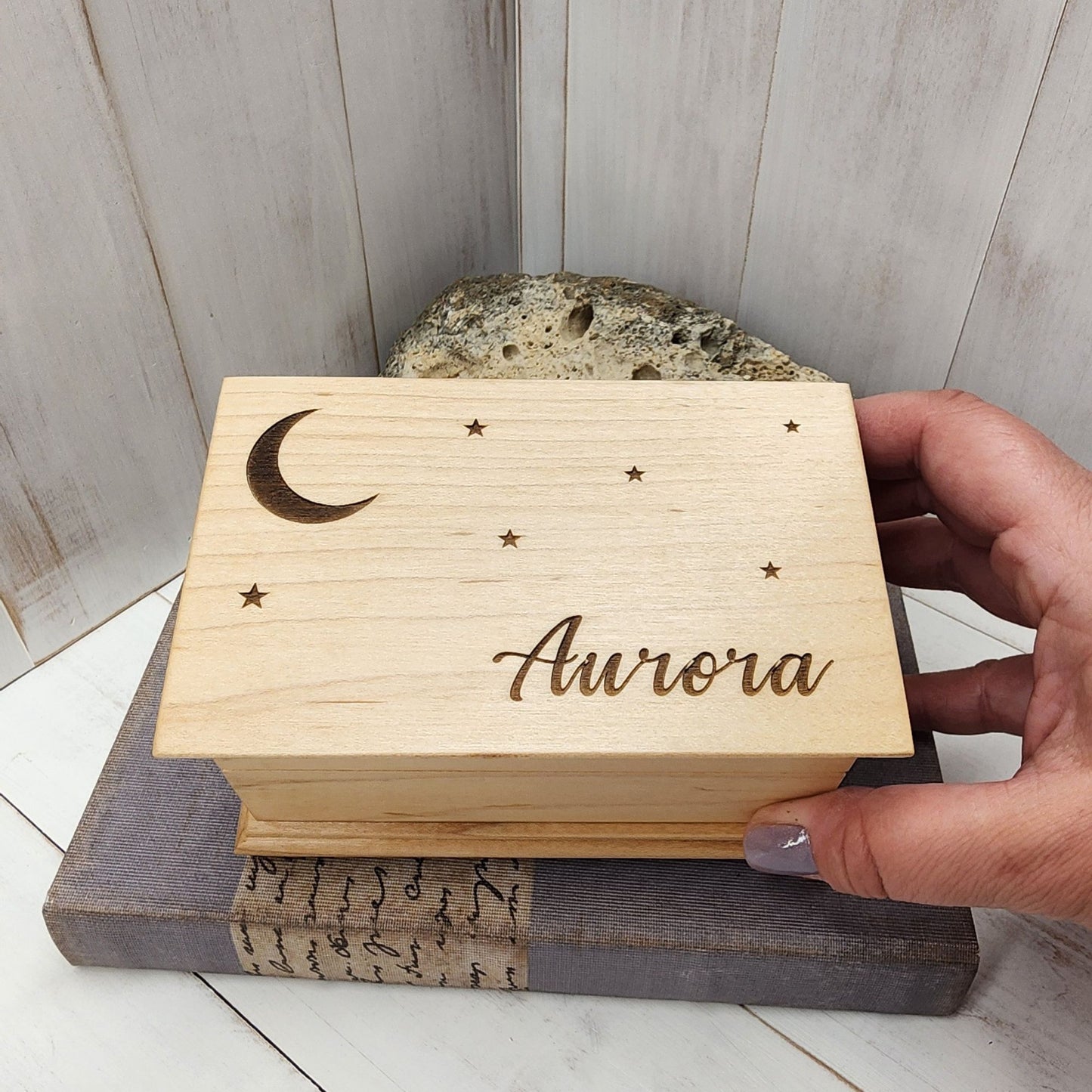Music box with moon and stars engraved on top along with the name Aurora in cursive font 