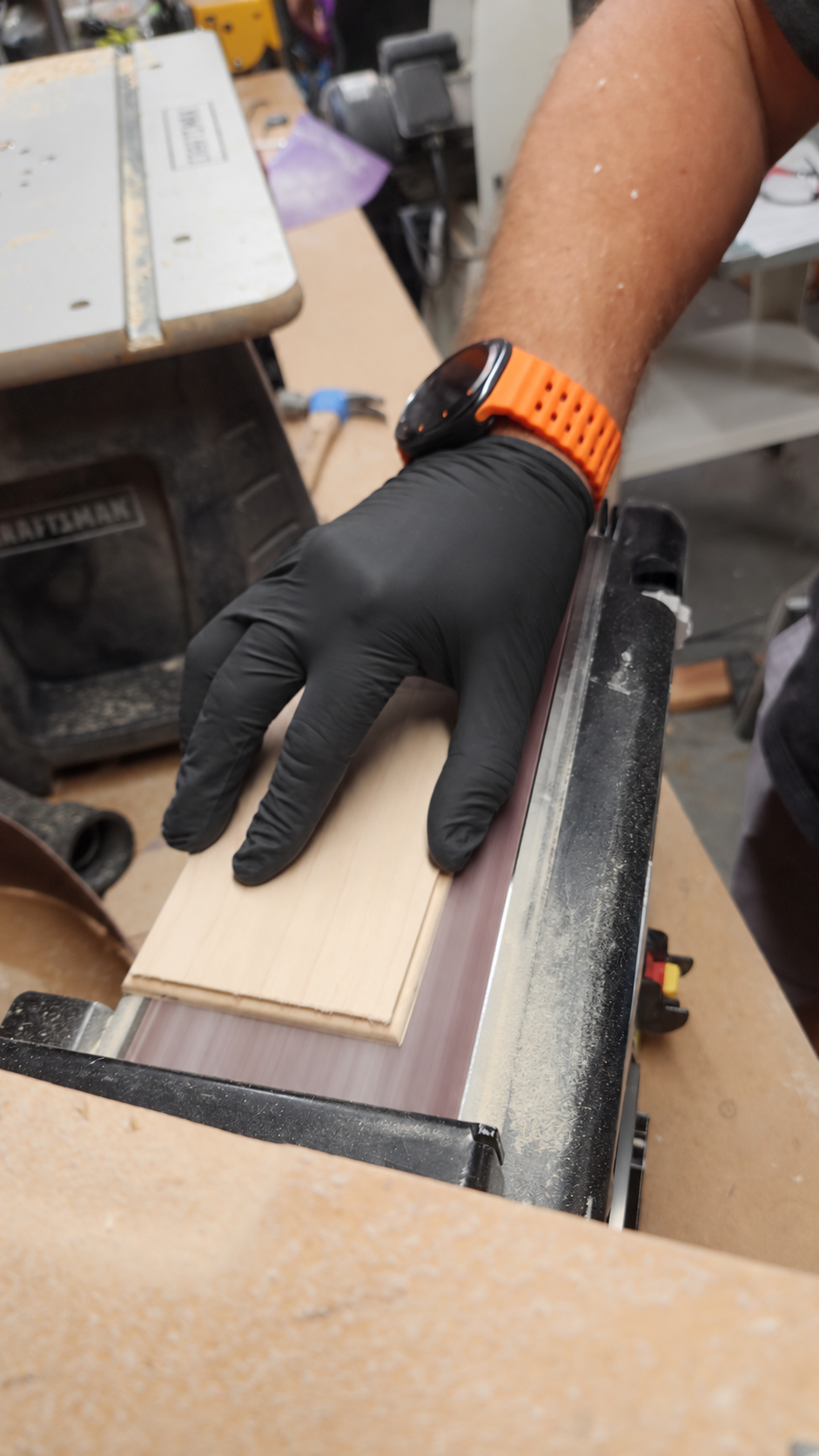 Hand sanding maple wood in our family workshop, wearing a black glove