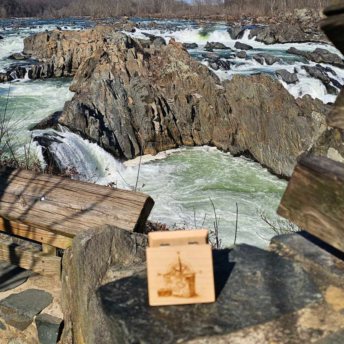 Rapids of a river with rocky formations and a wooden music box in the foreground.