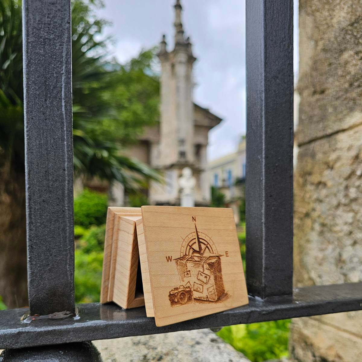 The traveling music box with a compass design on a metal gate with a blurred church in the background