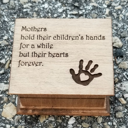 Music box with Mom quote engraved on the top along with a heart and a handprint, Mothers hold their children's hands for a while but their hearts forever